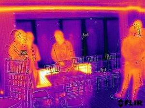 Thermal imaging image showing people and heat loss around window frame.